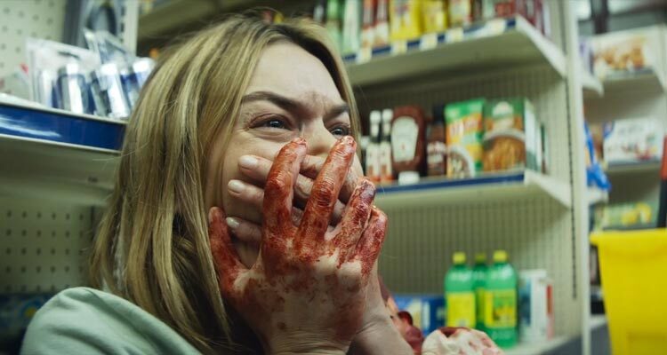 Night of the Hunted 2023 Movie Scene Camille Rowe as Alice holding her bloody hands on her mouth after the sniper killed her friend in a remote gas station