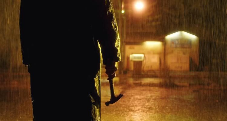 Open 24 Hours 2018 Movie Scene A killer in a raincoat holding a hammer in the rain in front of a remote gas station