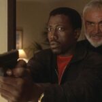 Rising Sun 1993 Movie Scene Sean Connery as John Connor standing behind Wesley Snipes as Web Smith holding a gun in his hand