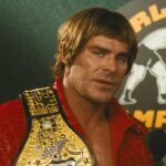 The Iron Claw 2023 Movie Scene Zac Efron as Kevin Von Erich holding his belt during an interview