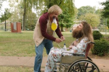 Dumb and Dumber To 2014 Movie Scene Jeff Daniels as Harry holding a catheter bag full of piss in his mouth while he fixes another one for Jim Carrey as Lloyd