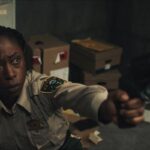 Jericho Ridge 2023 Movie Scene Nikki Amuka-Bird as Deputy Tabby Temple holding a gun pointed at the intruder in the police station